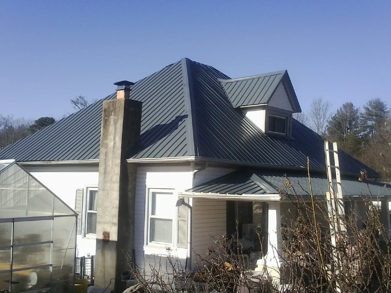 Dark blue standing seam metal roof on a white farmhouse with dormer — Slate & Tile Roof Repair by Roofing Brothers in Mansfield