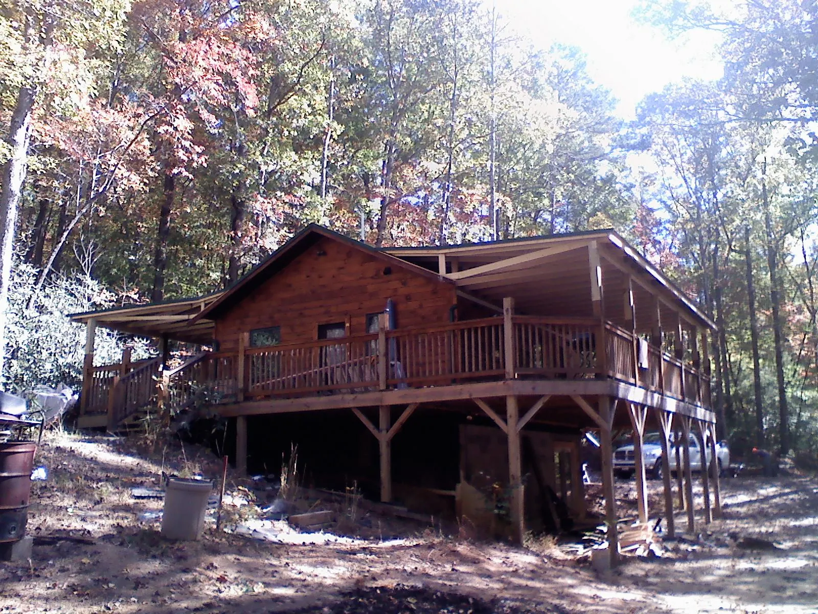 Log cabin with a wraparound porch and metal roof in the fall in Mansfield