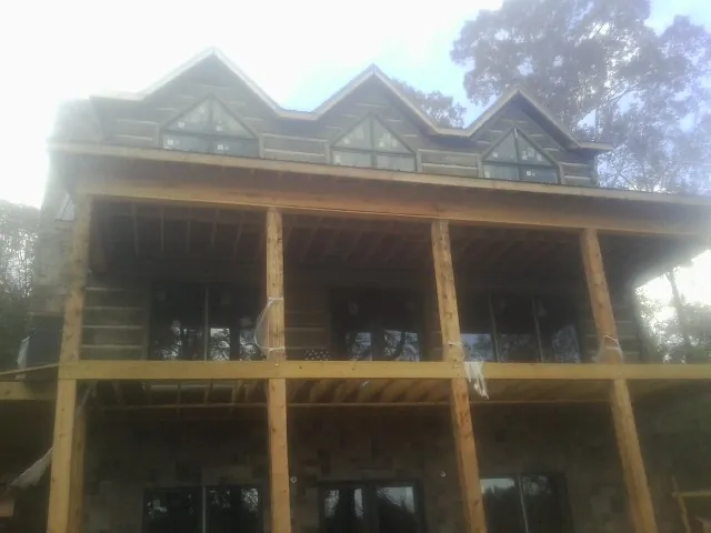 Dormers and porch framing on a large log home under construction — Roof Coating work by our crew in Mansfield