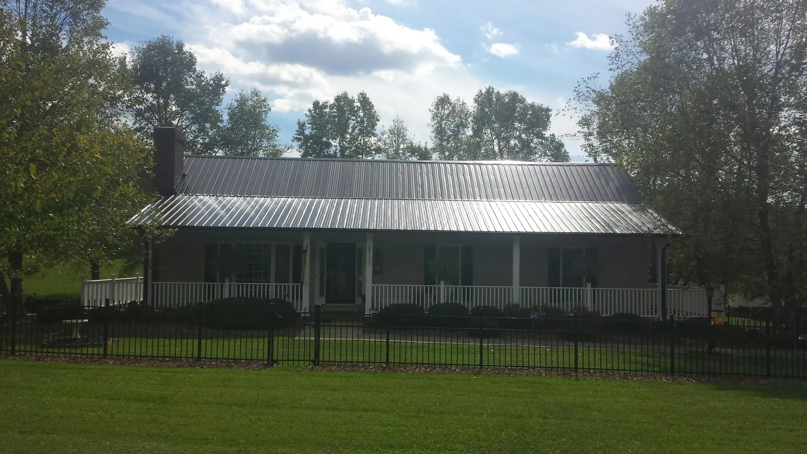 Gray metal roof on a brick ranch with a full width front porch — Gutter Guard Installation work by our crew in Mansfield