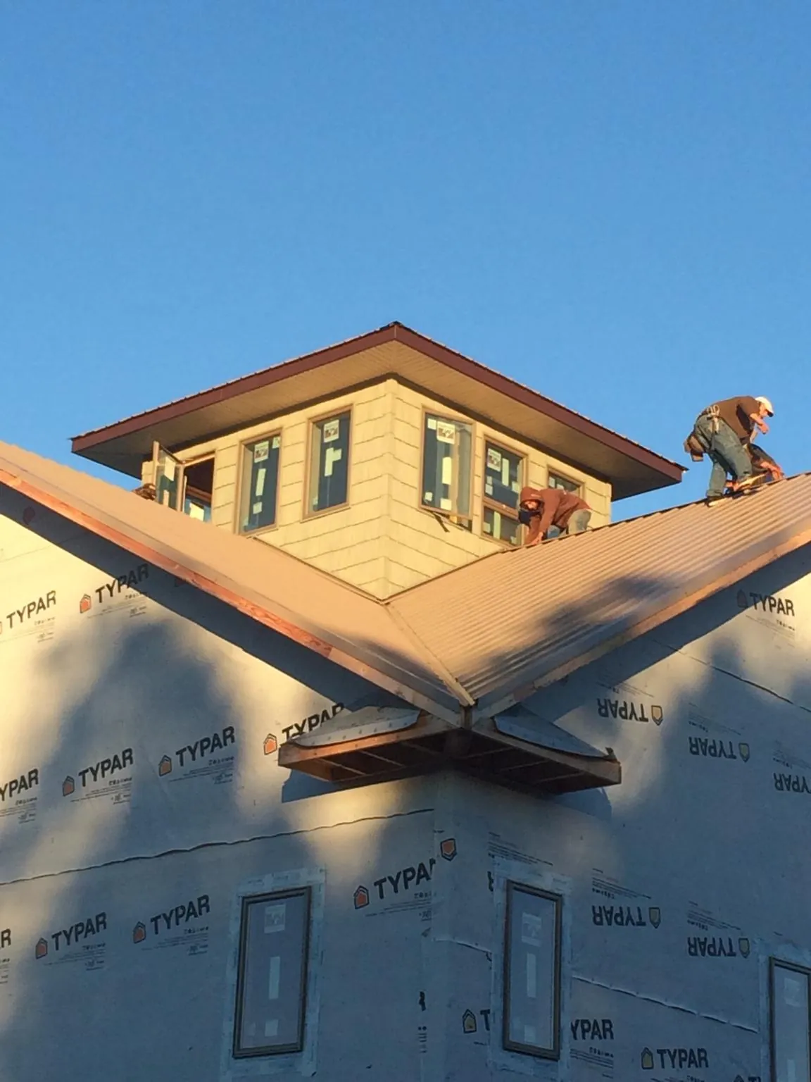 Roofers working around a rooftop cupola on a new metal roof at sunset — Roof Waterproofing in Mansfield by Roofing Brothers
